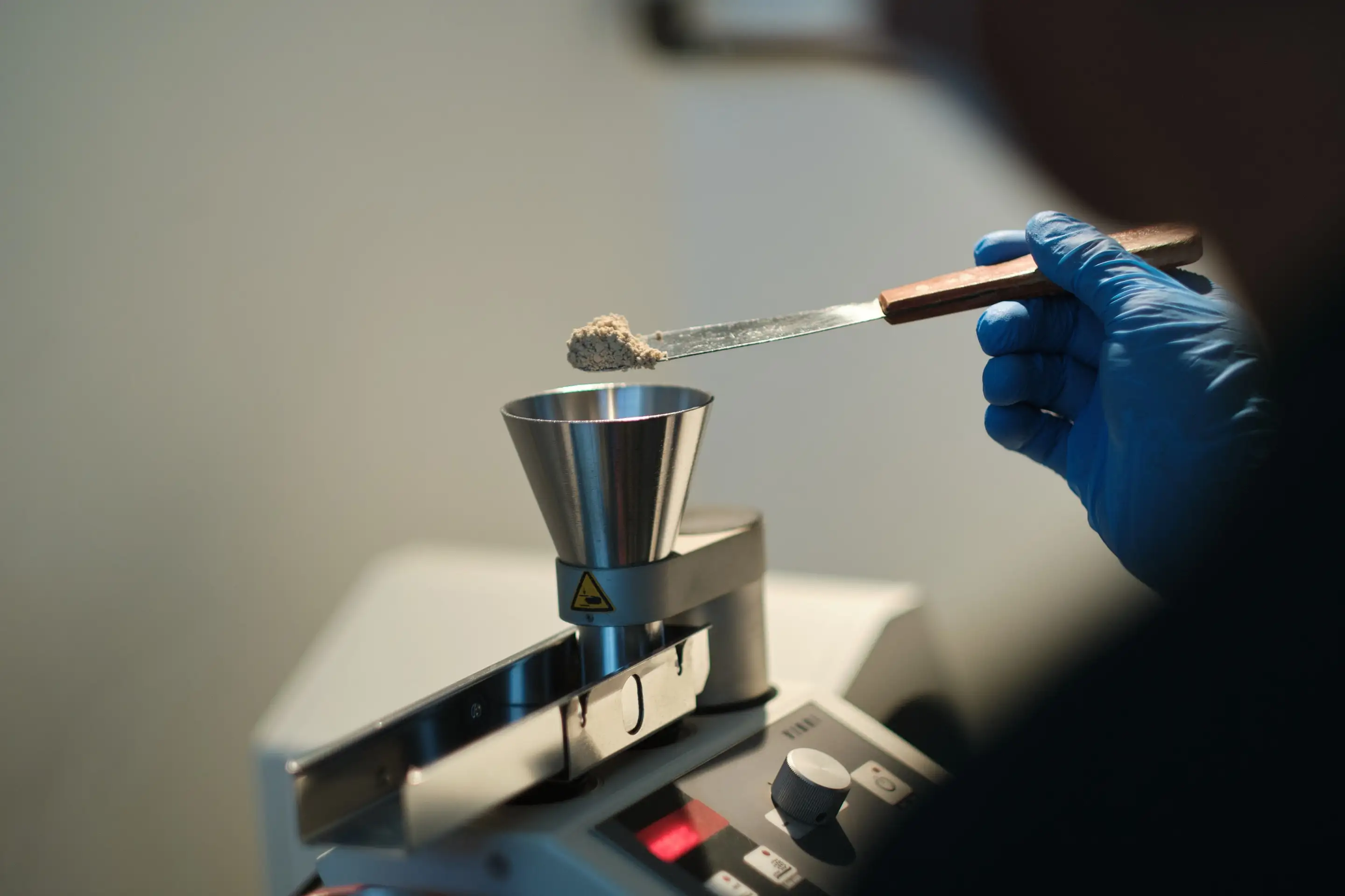 Gloved hand weighing chia powder on a precision balance
