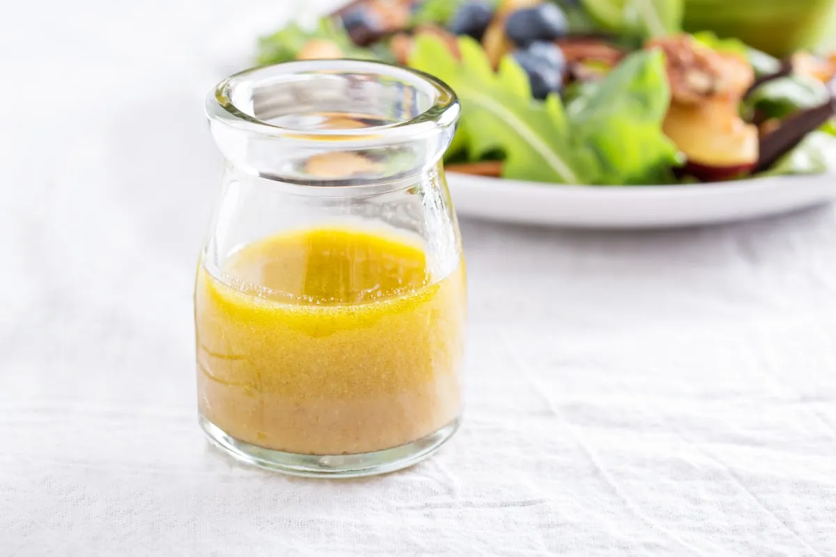 A jar of vinaigrette beside a plated salad