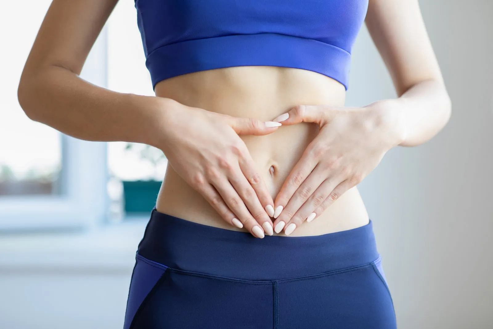 A woman resting both hands over her abdomen