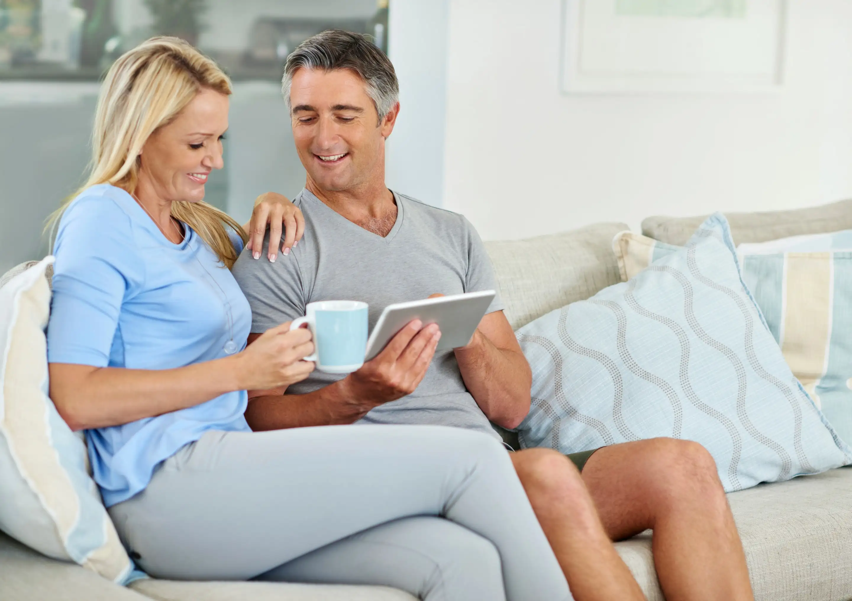 A mature couple relaxing on a sofa with a tablet